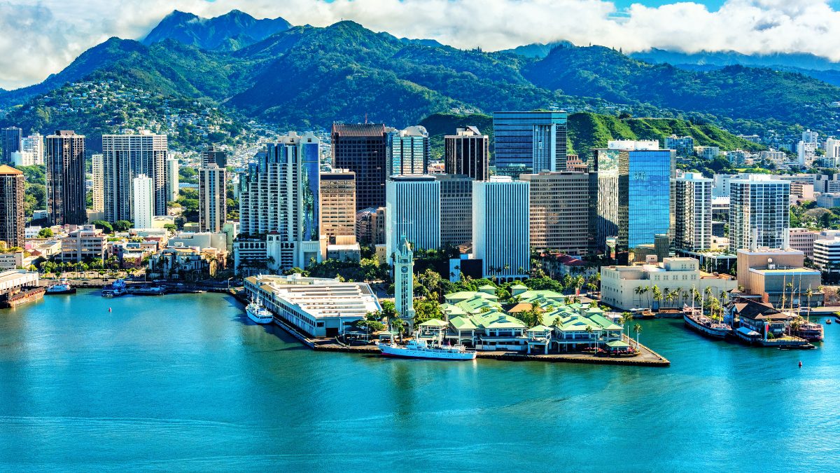 Downtown Honolulu skyline with turquoise waterfront and mountain backdrop on a clear day