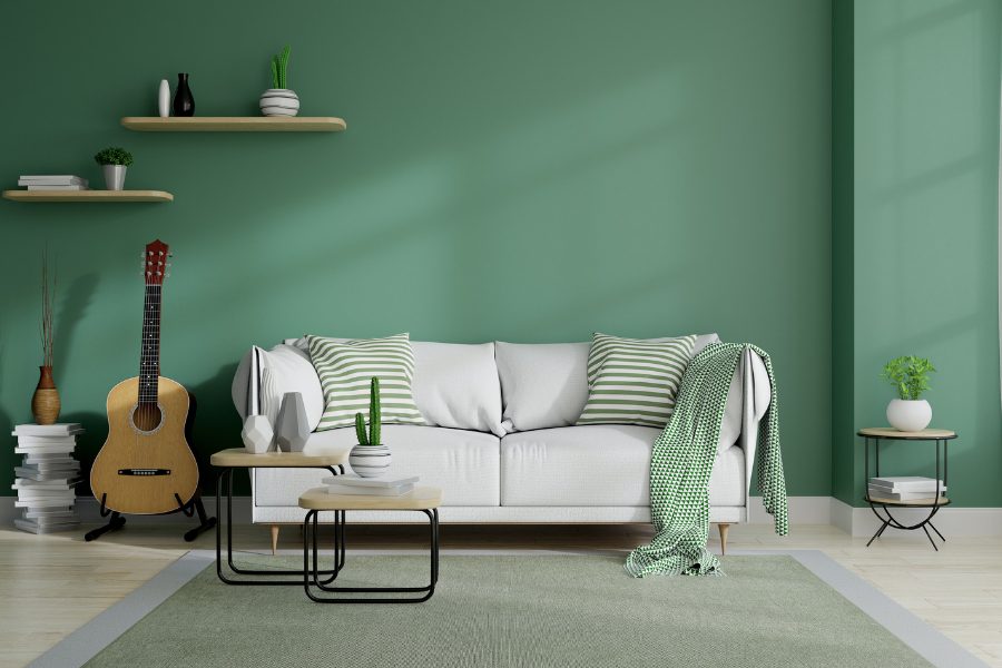 Living room with green color-drenched walls and decor, white sofa, and natural accents