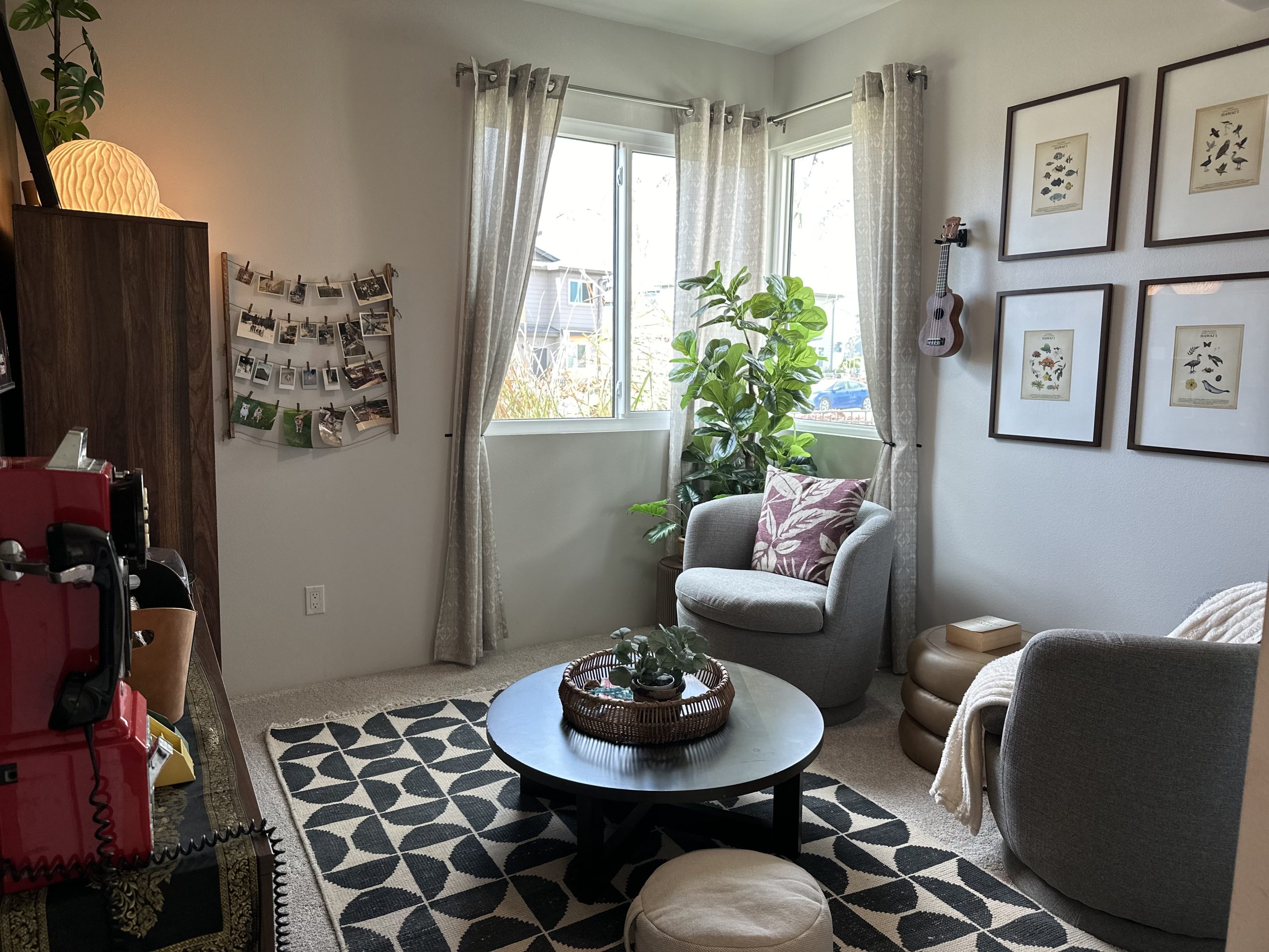 cozy staged living room with two gray swivel chairs, framed botanical art, and natural light from two windows